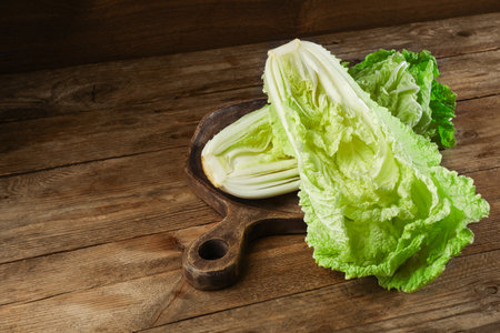 Halves of fresh ripe Chinese cabbage on wooden tableの写真素材