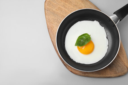 Pan with tasty fried egg on light gray background, top view. Space for textの写真素材