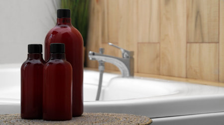 Bath foam and other personal hygiene products in bottles on wicker mat in bathroom, space for textの写真素材
