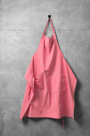 Clean red striped apron on gray tiled wallの写真素材