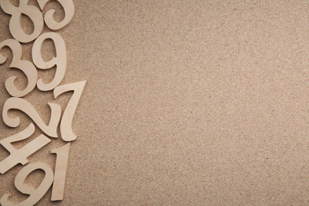 Wooden numbers on fiberboard, flat lay. Space for text