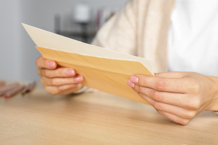 Woman holding greeting card on wooden table, closeupの写真素材