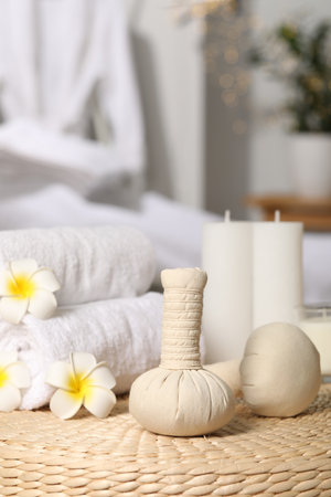 Herbal bags, candles, rolled towels and beautiful flowers on wicker surface indoors. spa productsの写真素材