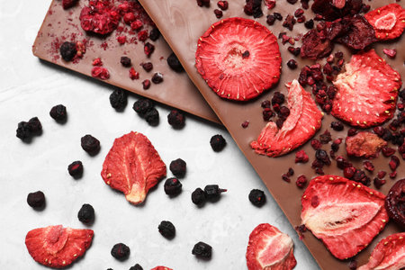 Chocolate bars with freeze dried berries on gray marble table, flat layの写真素材