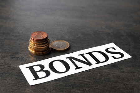 Paper with word Bonds and stacked coins on gray tableの写真素材
