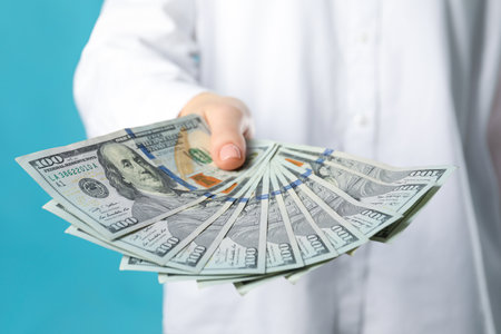 Woman holding dollar banknotes on turquoise background, closeup. money exchange conceptの写真素材