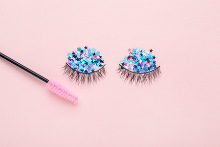 False eyelashes, sequins and mascara brush on pink background, flat layの写真素材