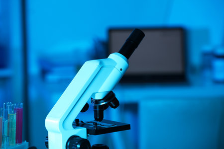 Modern microscope with glass slide in laboratory, toned in blue. Space for textの写真素材