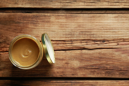 Spicy mustard in glass jar on wooden table. Space for text, top viewの写真素材