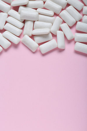 Tasty white chewing gums on pale pink background, flat lay. Space for text
