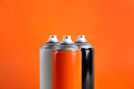 Colorful cans of spray paints on orange background, closeupの写真素材