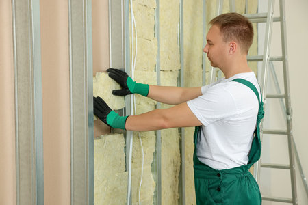 Worker installing thermal insulation material on wall indoorsの写真素材