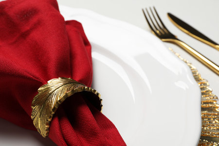 Plate with red fabric napkin, decorative ring and cutlery on white table, closeupの写真素材