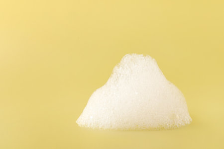 Drop of fluffy bath foam on pale orange background. Space for textの写真素材