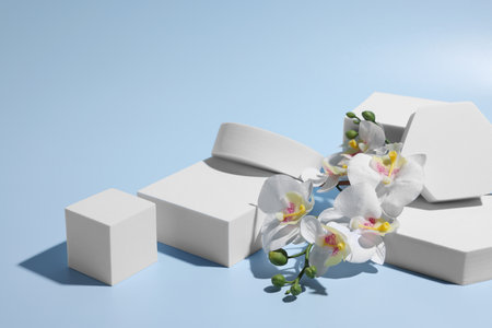 scene for product presentation. Podiums of different geometric shapes and orchid flowers on light blue backgroundの写真素材