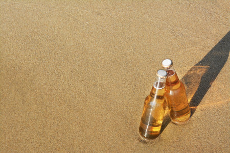 Bottles of cold beer on sandy beach, space for textの写真素材