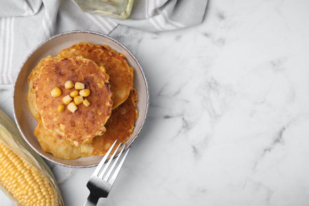 Tasty corn pancakes served on white marble table, flat lay. Space for text