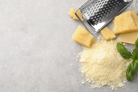 Flat lay composition with grater, basil, parmesan cheese on gray table. Space for textの写真素材