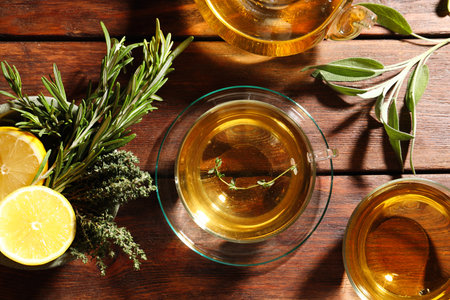 Aromatic herbal tea, fresh rosemary, thyme and lemon on wooden table, flat layの写真素材