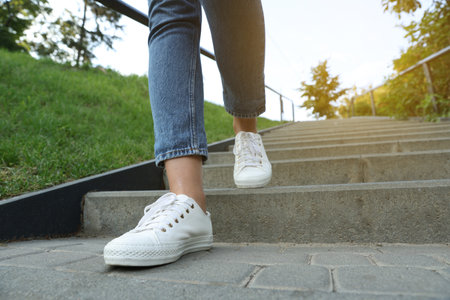 Woman in stylish black sneakers walking down stairs, closeupの写真素材