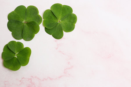 Beautiful green clover leaves on pink marble table, flat lay. Space for textの写真素材