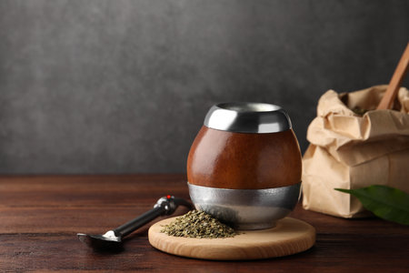 Calabash with mate tea and bombilla on wooden table. Space for text