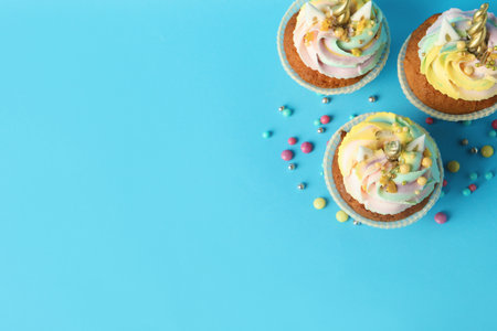 Cute sweet unicorn cupcakes on light blue background, flat lay. Space for textの写真素材