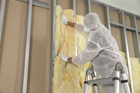 Worker insulating wall using ladder indoors, low angle view. Space for textの写真素材
