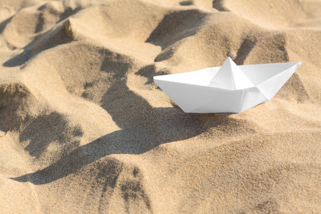 One white paper boat on sandy beach, space for textの写真素材