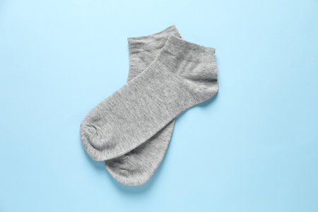 Pair of gray socks on light blue background, flat lay