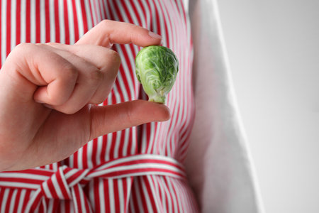Woman showing fresh brussel sprout on white background, closeupの写真素材