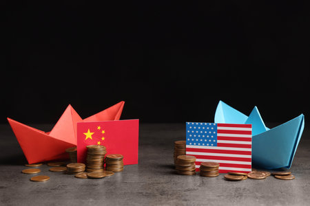 American and Chinese flags, coins with paper boats on gray table against black background . trade war conceptの写真素材