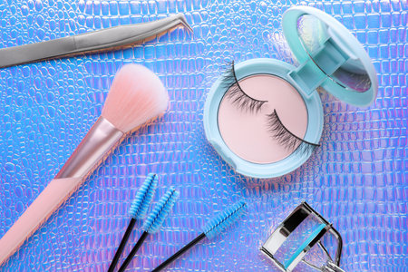 Flat lay composition with false eyelashes and cosmetic products on texture colorful backgroundの写真素材