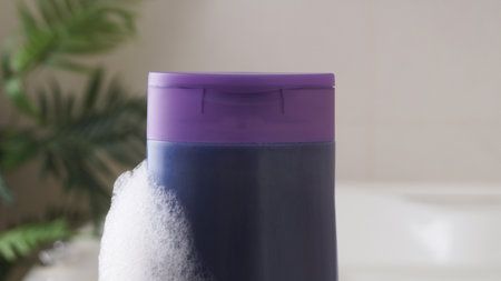 Purple bottle of bubble bath with foam indoors, closeupの写真素材