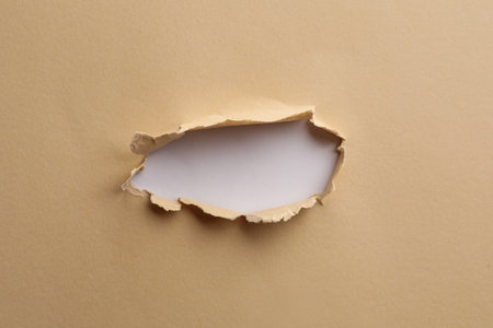 Hole in light beige paper on white backgroundの写真素材