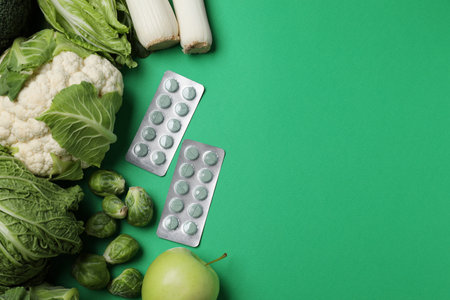 Blisters of pills and foodstuff on green background, flat lay with space for text. Prebiotic supplementsの写真素材