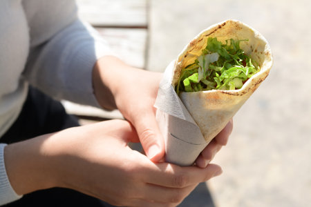 Woman holding delicious vegetable roll outdoors, closeup