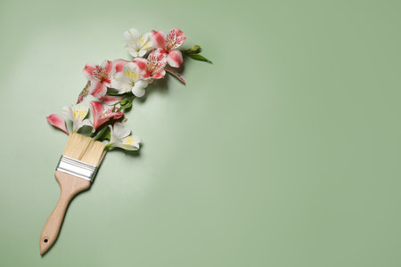 Composition with painting brush and beautiful alstroemerias on green background, above view. Space for textの写真素材
