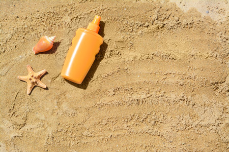 Blank bottle of sunscreen, starfish and seashell on sand, flat lay. Space for textの写真素材