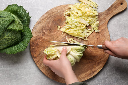 Woman cutting fresh ripe cabbage at gray table, top viewの写真素材