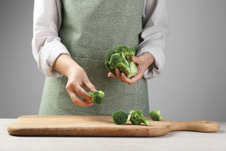 Woman with fresh broccoli on wooden table, closeupの写真素材