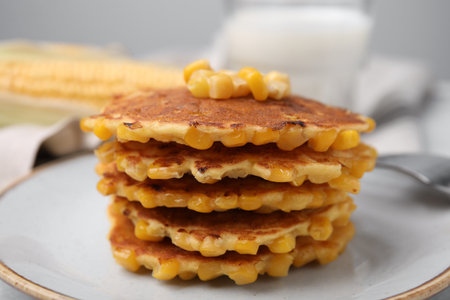 Tasty corn pancakes on white plate, closeup