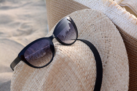 Hat and bag with beautiful sunglasses on sandy beach, closeupの写真素材