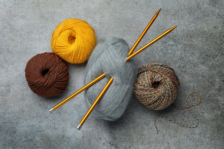 Soft woolen yarns and knitting needles on gray table, flat layの写真素材
