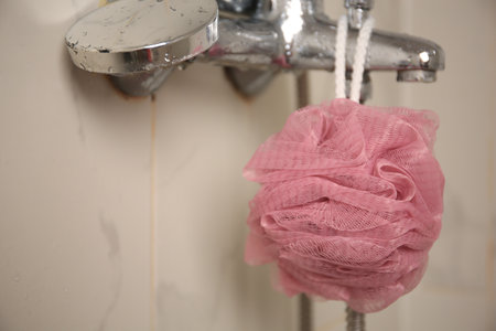 Pink shower puff hanging on faucet in bathroom, closeupの写真素材