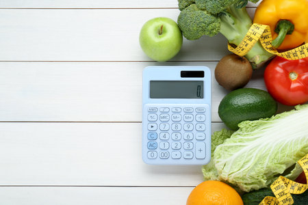 Calculator and food products on white wooden table, flat lay with space for text. weight loss conceptの写真素材