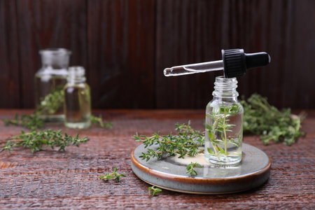 Thyme essential oil and fresh plant on wooden table, space for textの写真素材