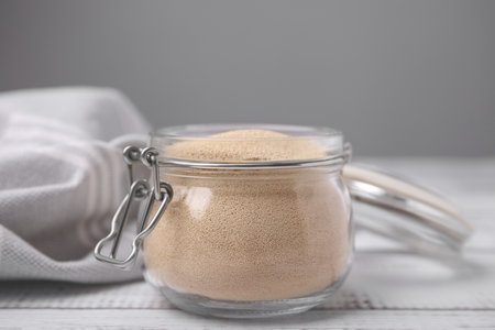 Granulated yeast in glass jar on white wooden table, closeupの写真素材