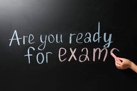 Woman writing phrase Are You Ready For Exams on blackboard, closeupの写真素材
