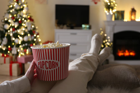 Woman with popcorn watching TV in room decorated for Christmas, closeupの写真素材